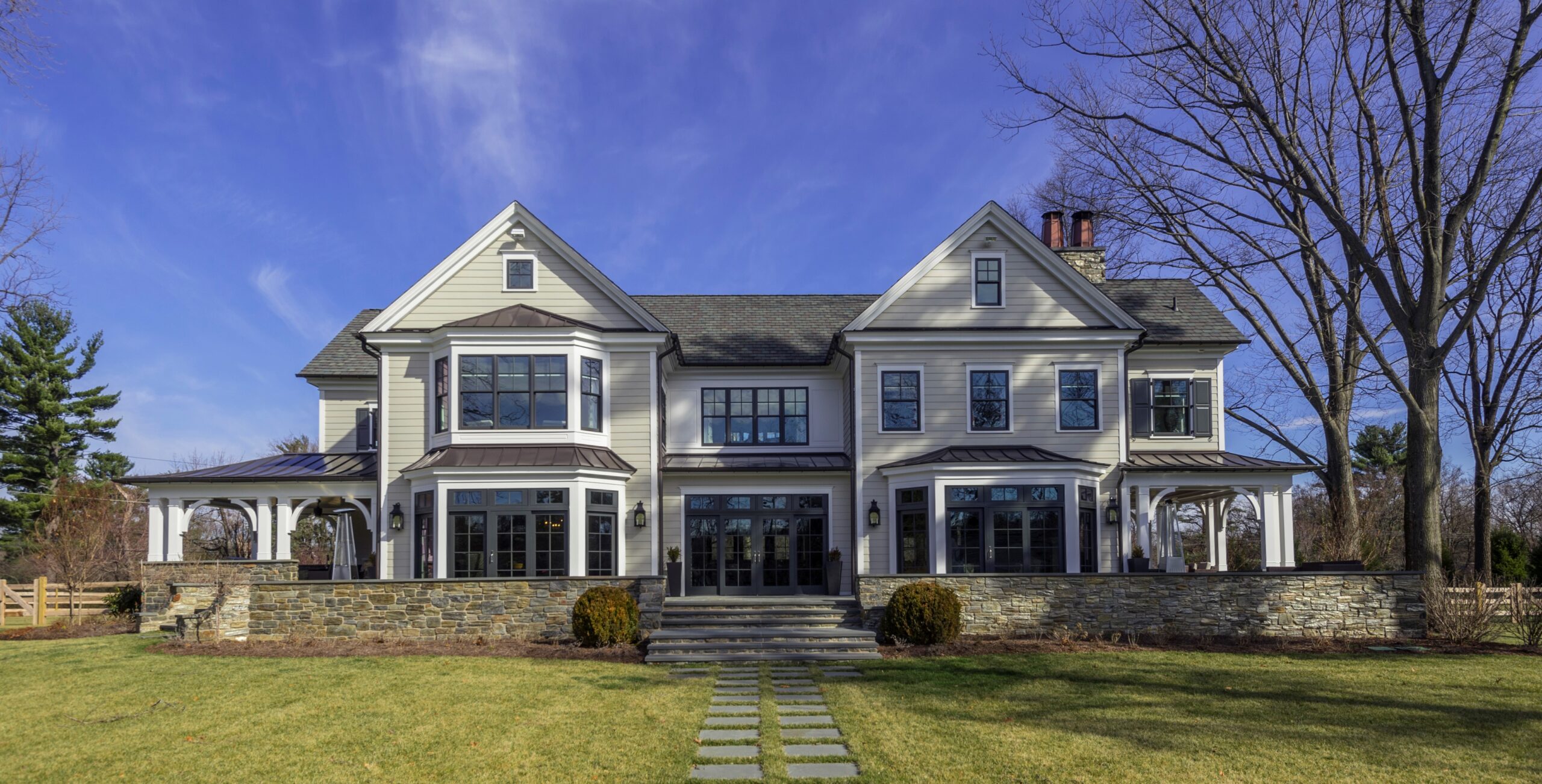 Modern farmhouse exterior elevation featuring white clapboard siding, stone base, multiple gables, and extensive glazing.