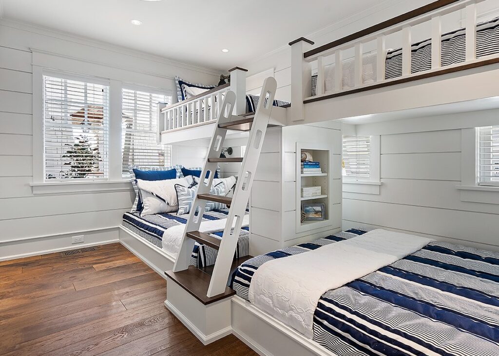 Modern children's bedroom with white shiplap walls, built-in bunk bed with integrated storage, and hardwood flooring.
