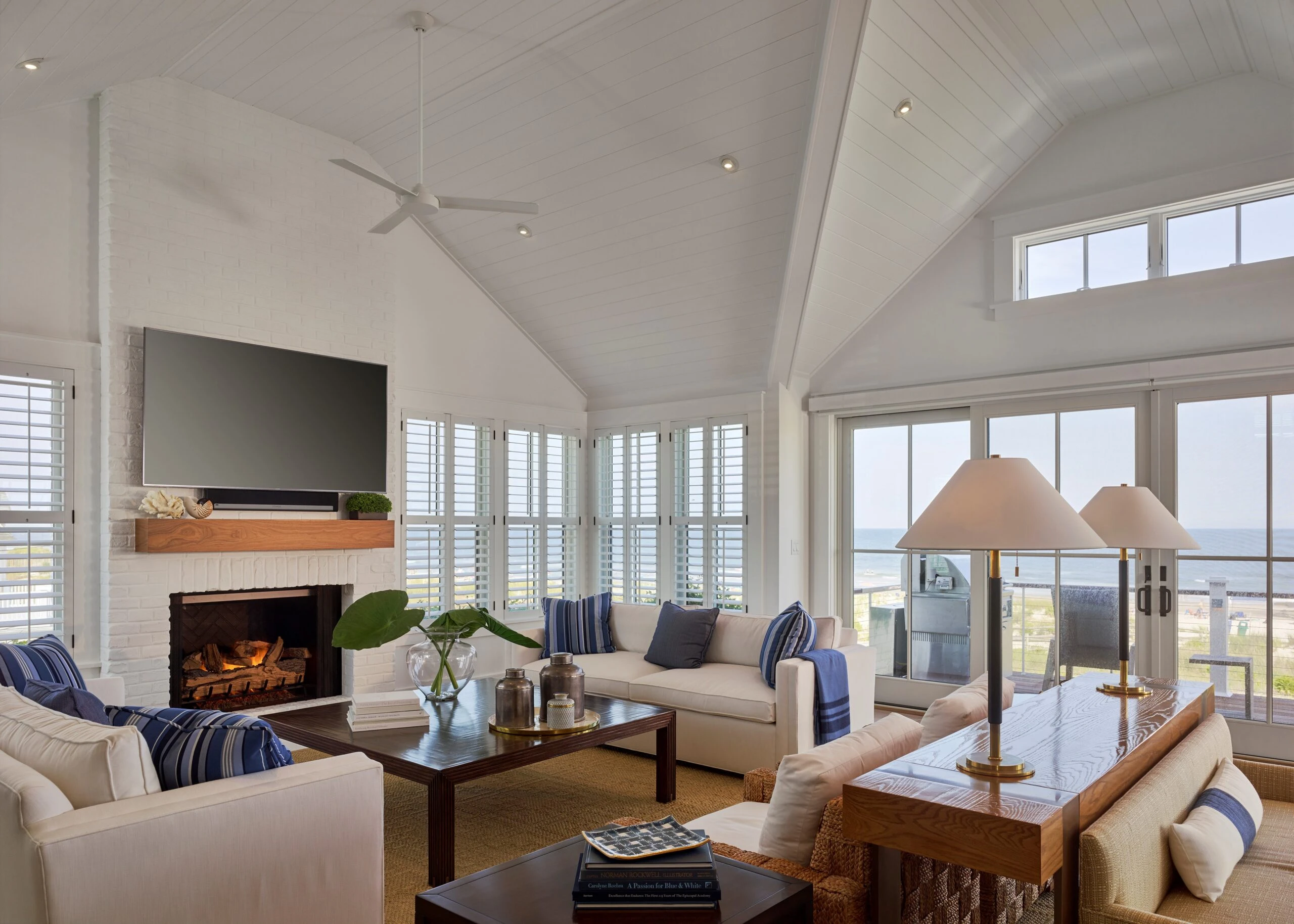 Modern coastal living room with vaulted ceiling, fireplace, extensive glazing, and ocean views.