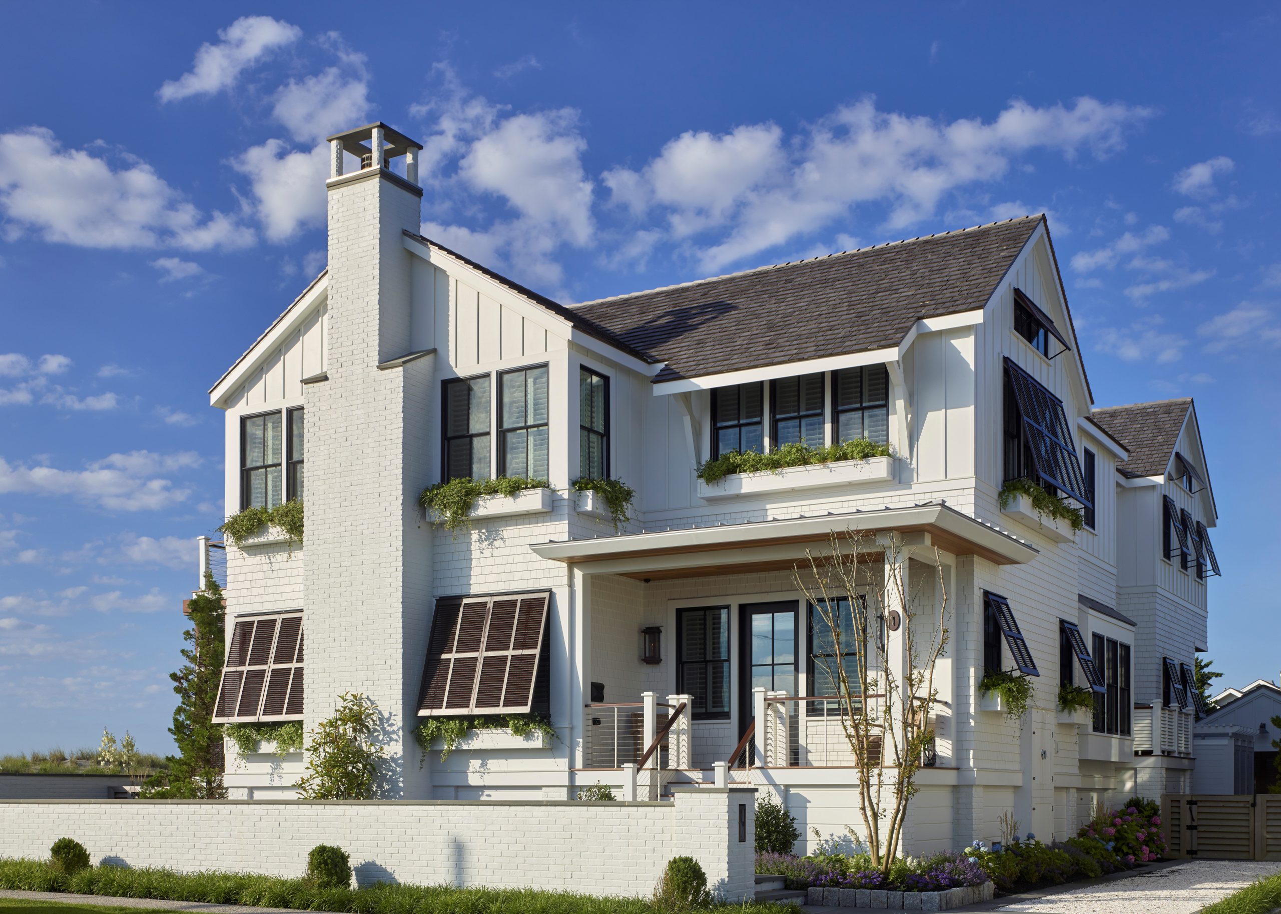 Modern farmhouse with white brick and board-and-batten siding, black-trimmed windows, and a prominent chimney.