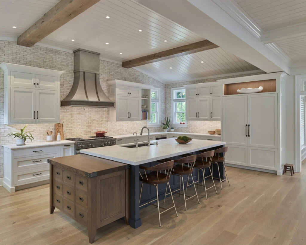 Modern farmhouse kitchen with white cabinetry, exposed timber beams, brick backsplash, and large island with seating.