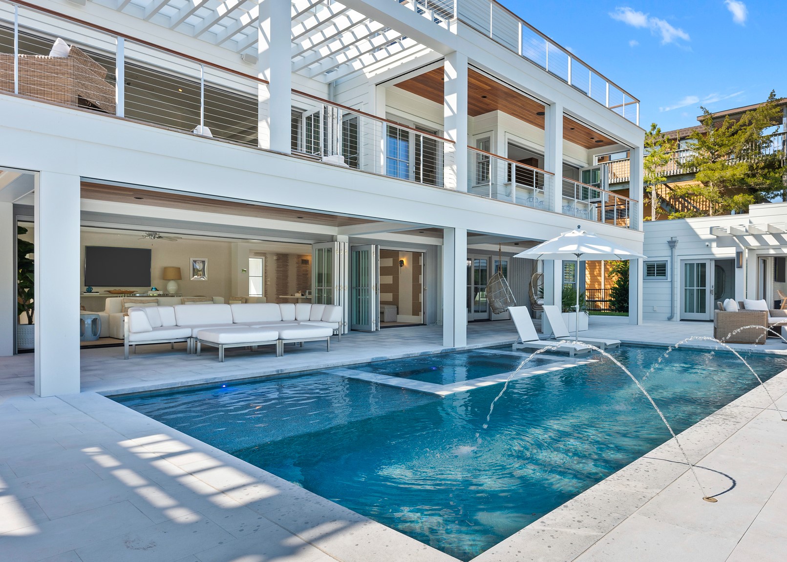 Modern residential home with white facade, glass sliding doors, and attached swimming pool with spa jets.