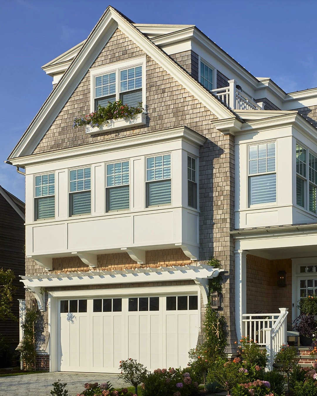 Modern coastal residence with shingled facade, white trim, multi-level design, and integrated garage below main living spaces.