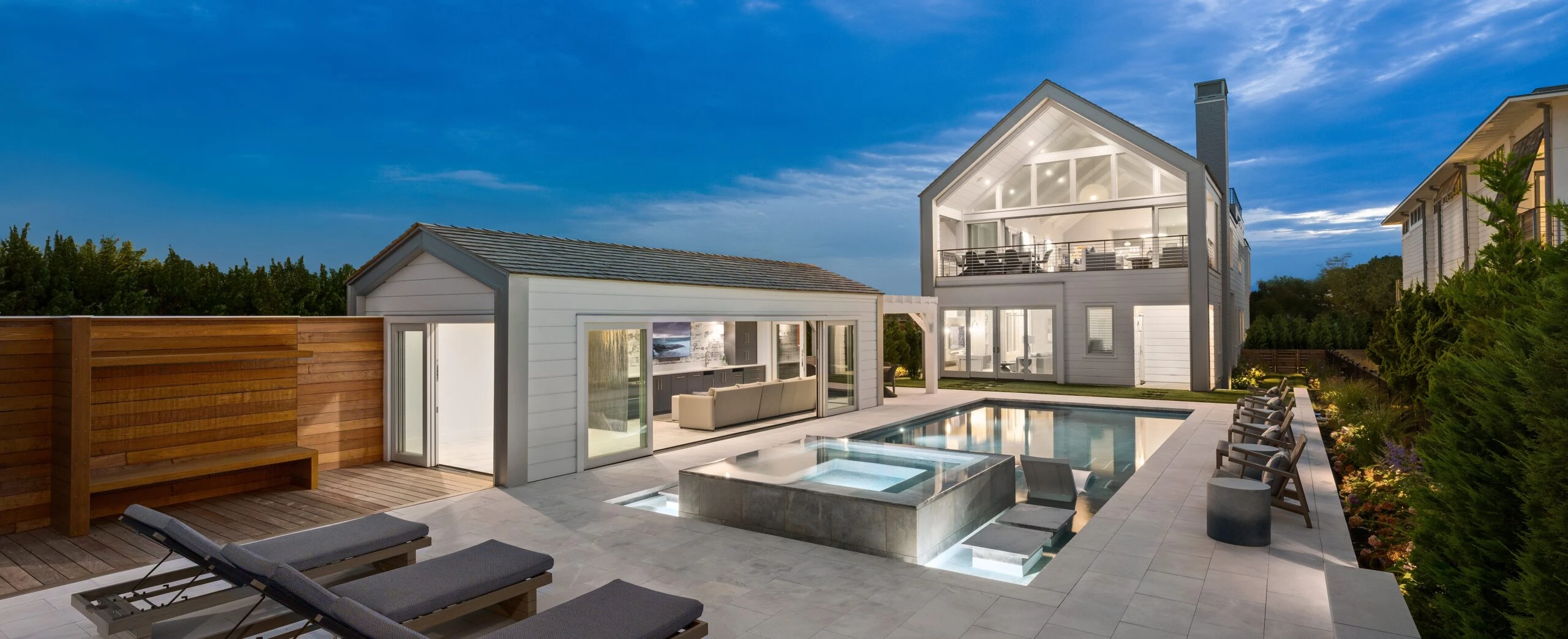 Modern residential home with clerestory windows, glass sliding doors, and integrated pool and spa on paved terrace.